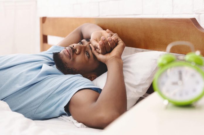 Black man in bed suffering from insomnia and sleep disorder
